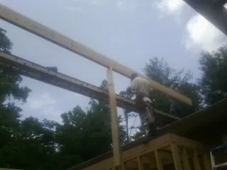 Carpenter setting a ridge beam over a new addition frame — Ice Dam Removal by Roofing Brothers in Ronco
