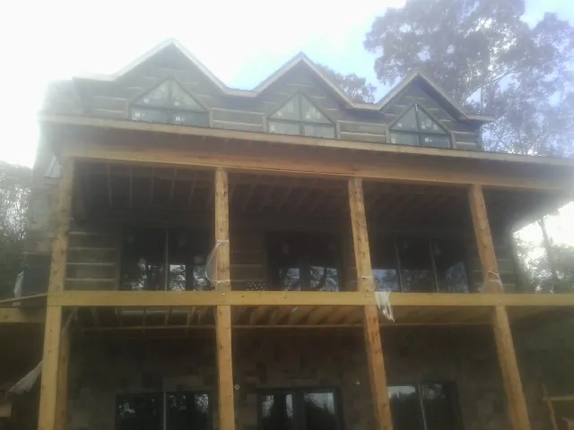 Dormers and porch framing on a large log home under construction — Roof Coating work by our crew in Ronco
