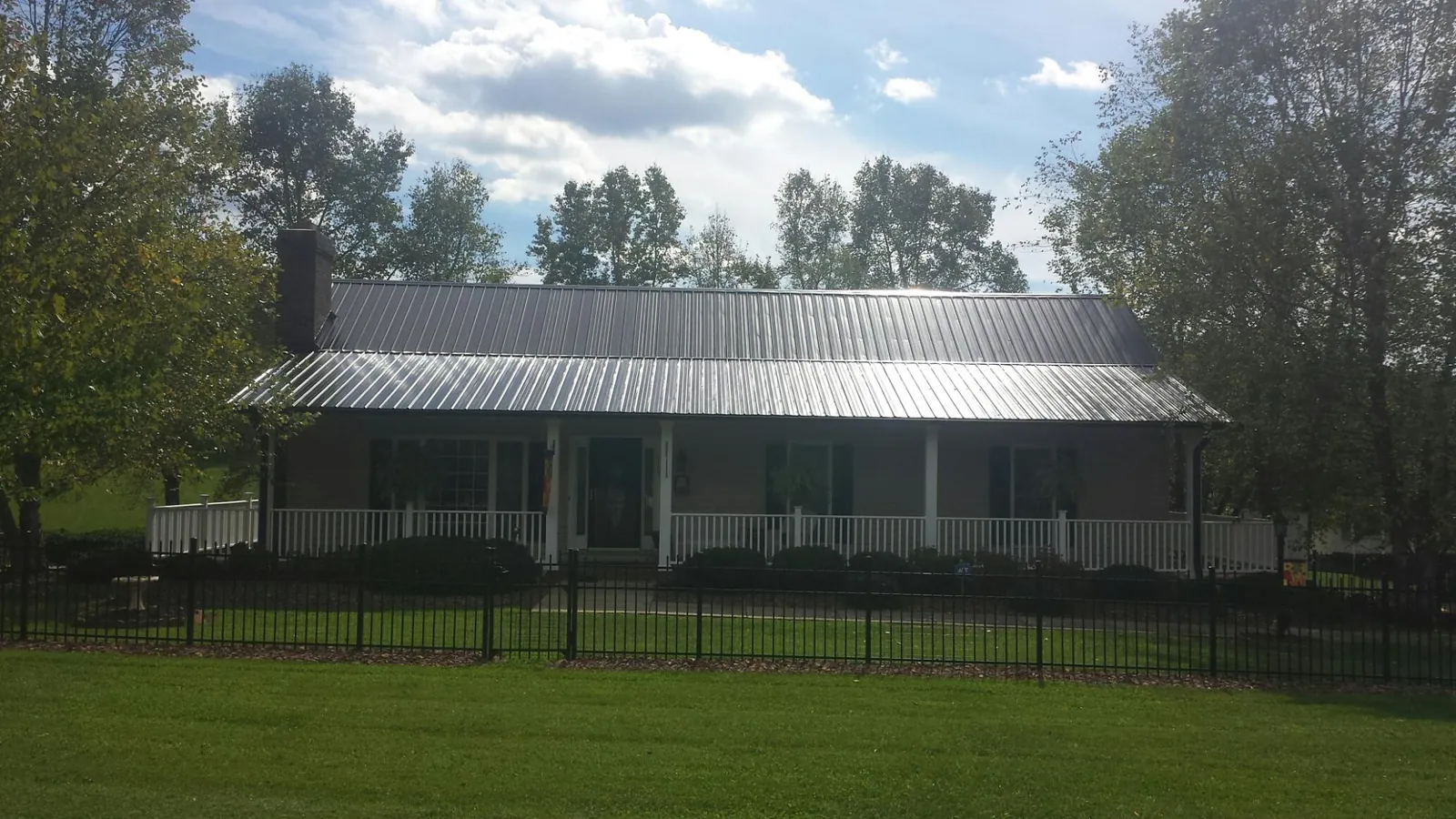 Gray metal roof on a brick ranch with a full width front porch — Gutter Guard Installation work by our crew in Ronco