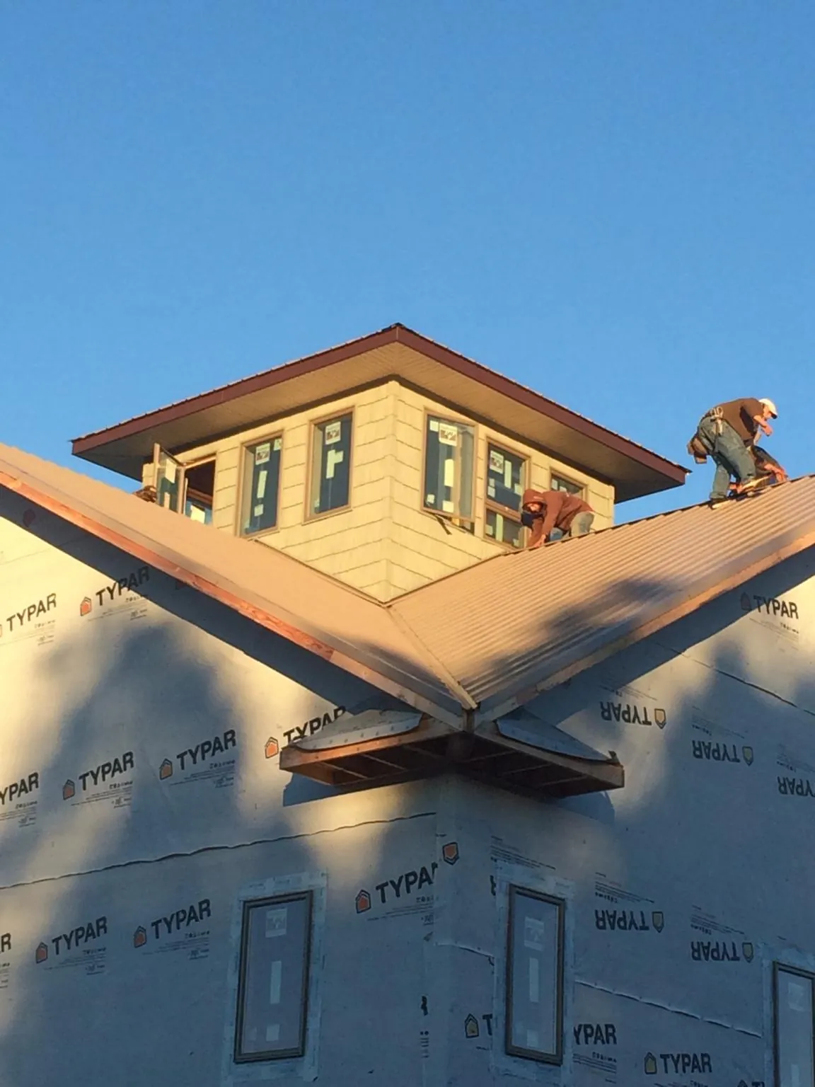 Roofers working around a rooftop cupola on a new metal roof at sunset — Roof Waterproofing in Ronco by Roofing Brothers